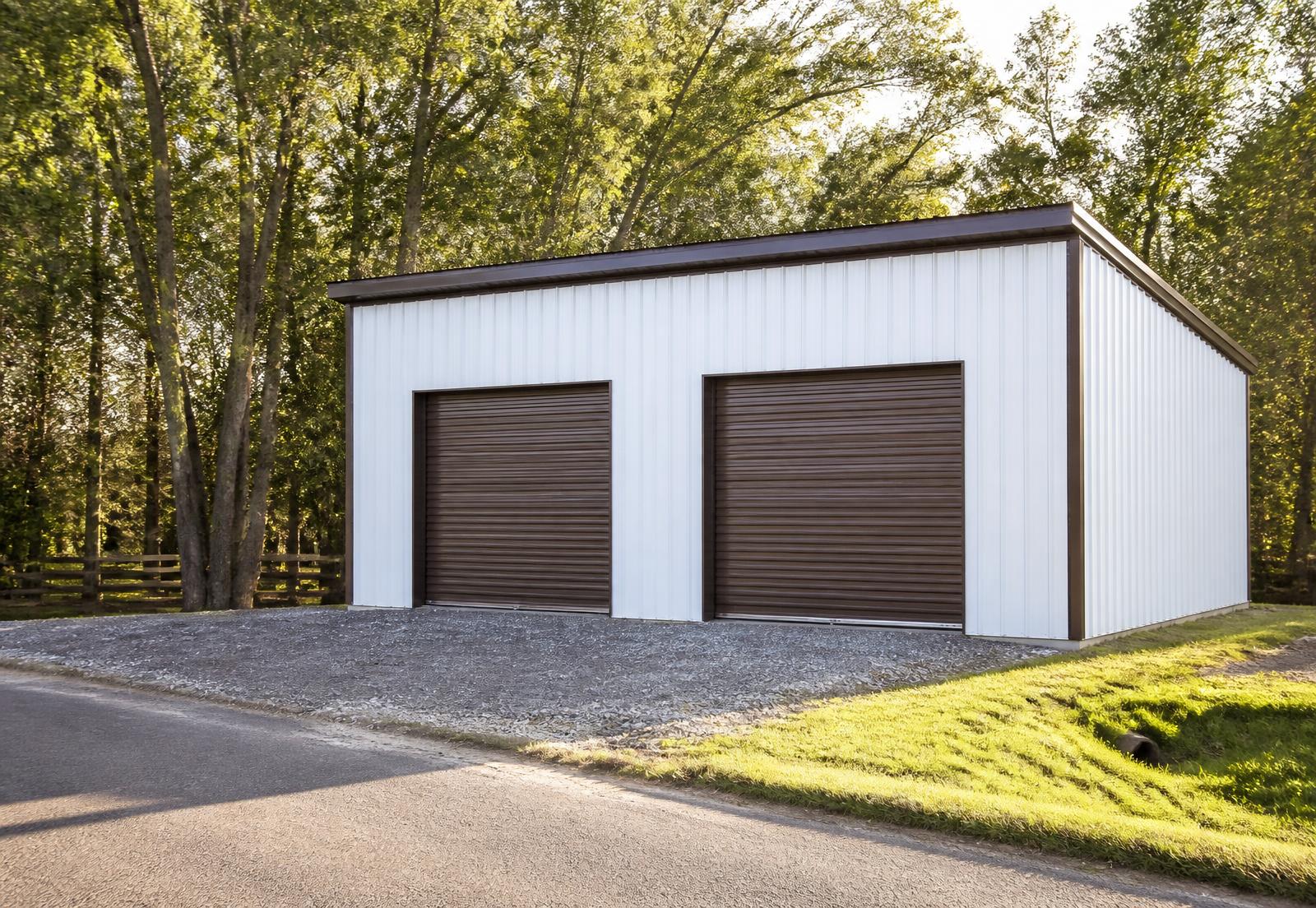 White steel building with two roll-up doors and a walk-in door on a gravel lot